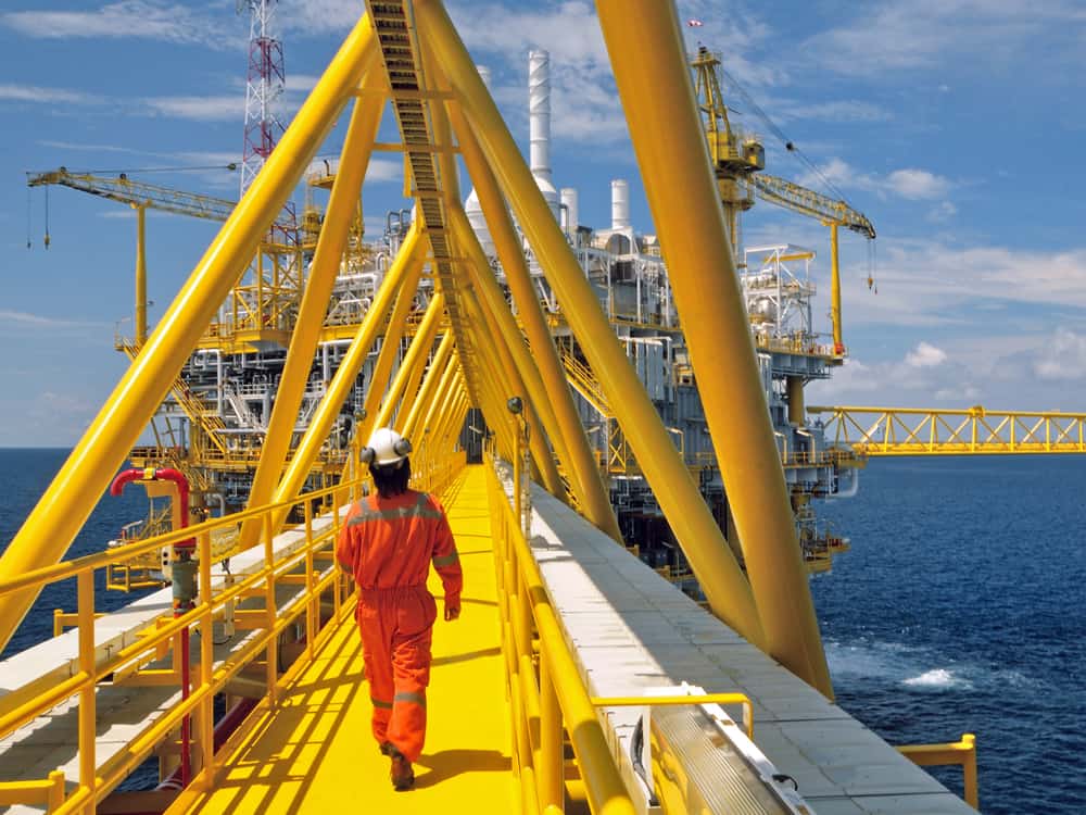 A worker walks across a bridge of an oil platform