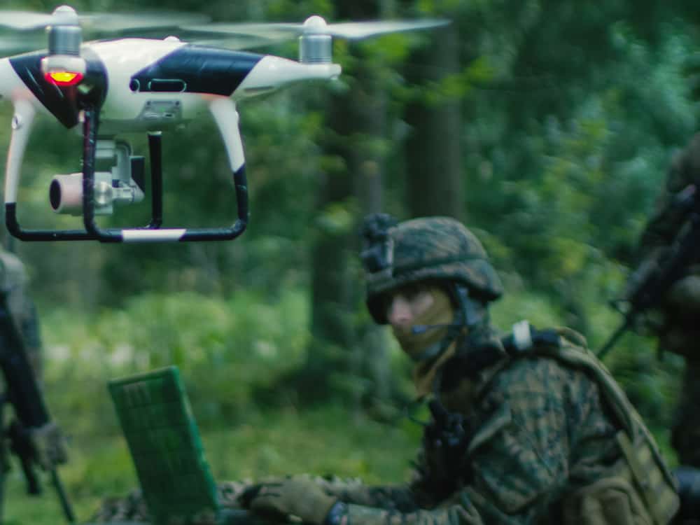 Soldiers in camouflage use a drone in the woods